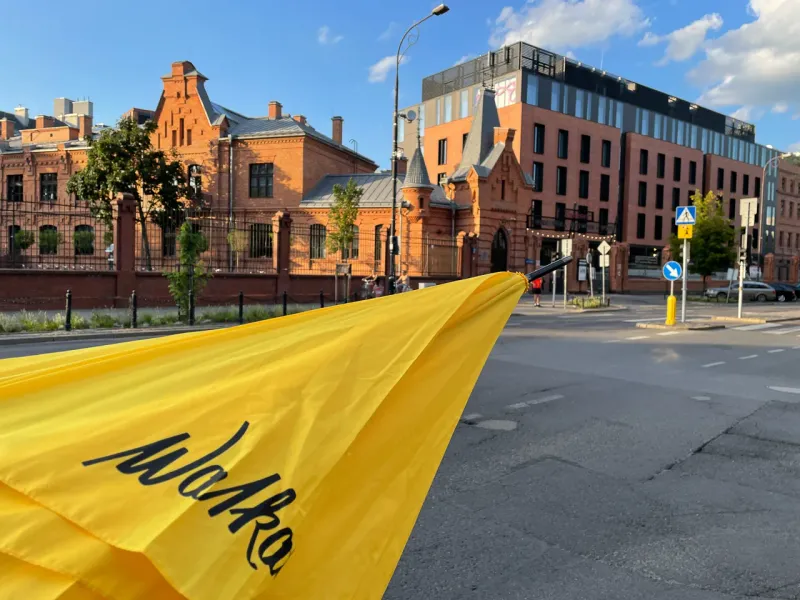 Yellow Mokka umbrella in Warsaw, Poland, showcasing historical and modern architecture.