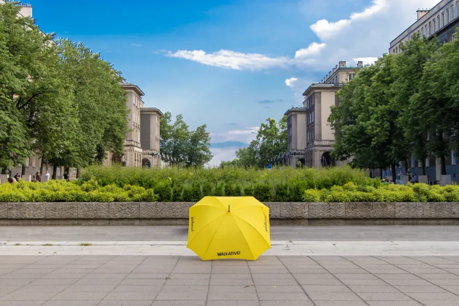 Yellow umbrella on a city street, inviting you to join a Walkative tour.