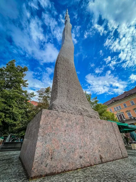 Tall abstract stone monument in Wrocław, Poland, against a blue sky.