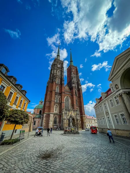 Wrocław Cathedral, a stunning Gothic landmark, stands tall against a vibrant blue sky.