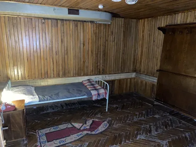 A simple historical room with a single bed and wooden walls.