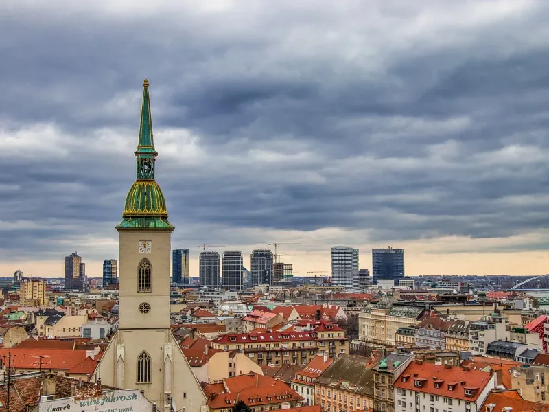 St. Martin's Cathedral tower with green spire and clock face overlooking Bratislava's old town and modern city skyline und...