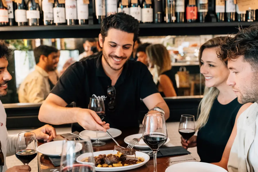 A group of friends shares food and red wine at a table in a Madrid tapas bar.