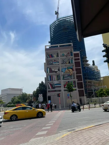 A street scene featuring a building with a large mural of bookshelves.