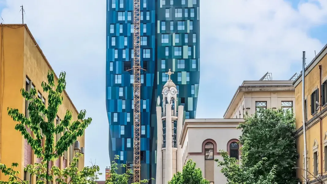Modern skyscraper and historic building in a city.