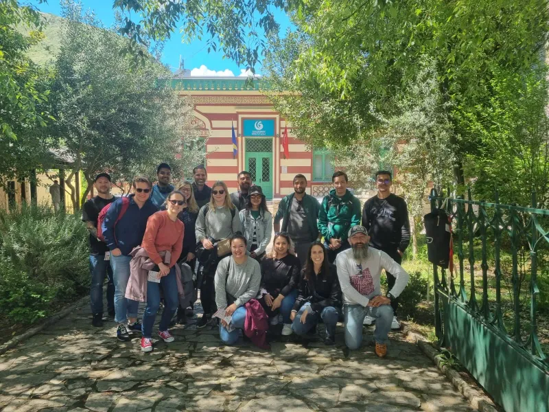 Happy tourists on a group tour pose for a photo in front of a beautiful building.