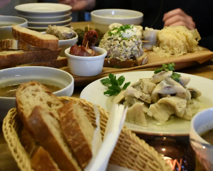 Traditional Polish food including herring, bread, and soup on a table in Krakow.
