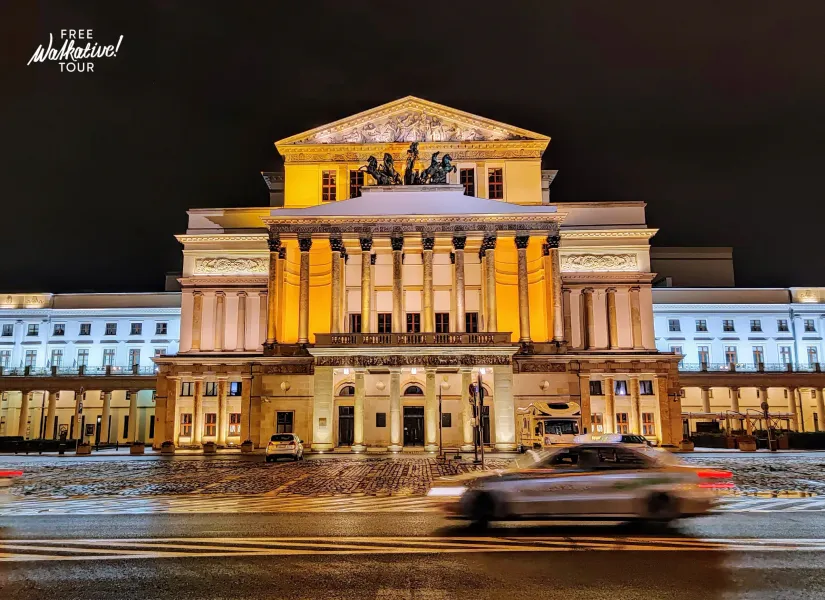 Grand Theatre in Warsaw at night, with a classical facade, columns, and sculptures, illuminated by warm lights. Snow on th...