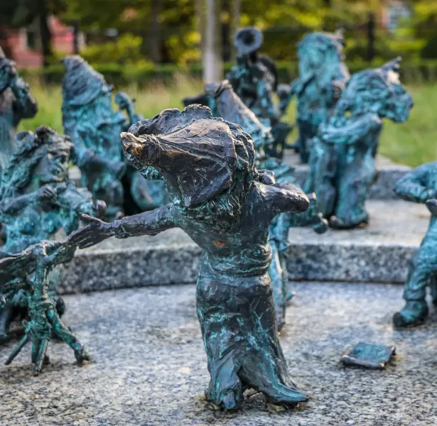 Group of bronze dwarf sculptures with green patina in Wroclaw. One dwarf in foreground extends its arm towards another on ...