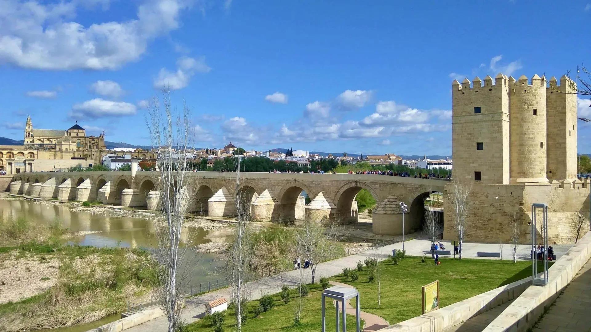 Roman Bridge over Guadalquivir River in Cordoba, with Calahorra Tower and Mezquita-Cathedral in the background under a blue s