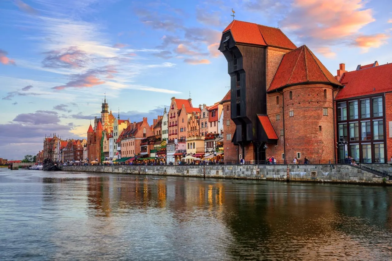Historic waterfront of Gdansk with the medieval Crane (Żuraw) building, colorful houses, and reflections on the Motława River