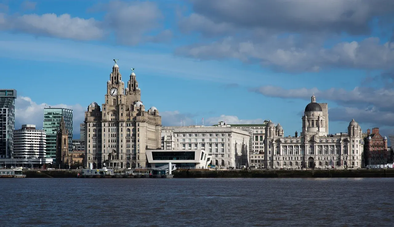 Liverpool waterfront with the Royal Liver Building, Cunard Building, and Port of Liverpool Building under a partly cloudy sky