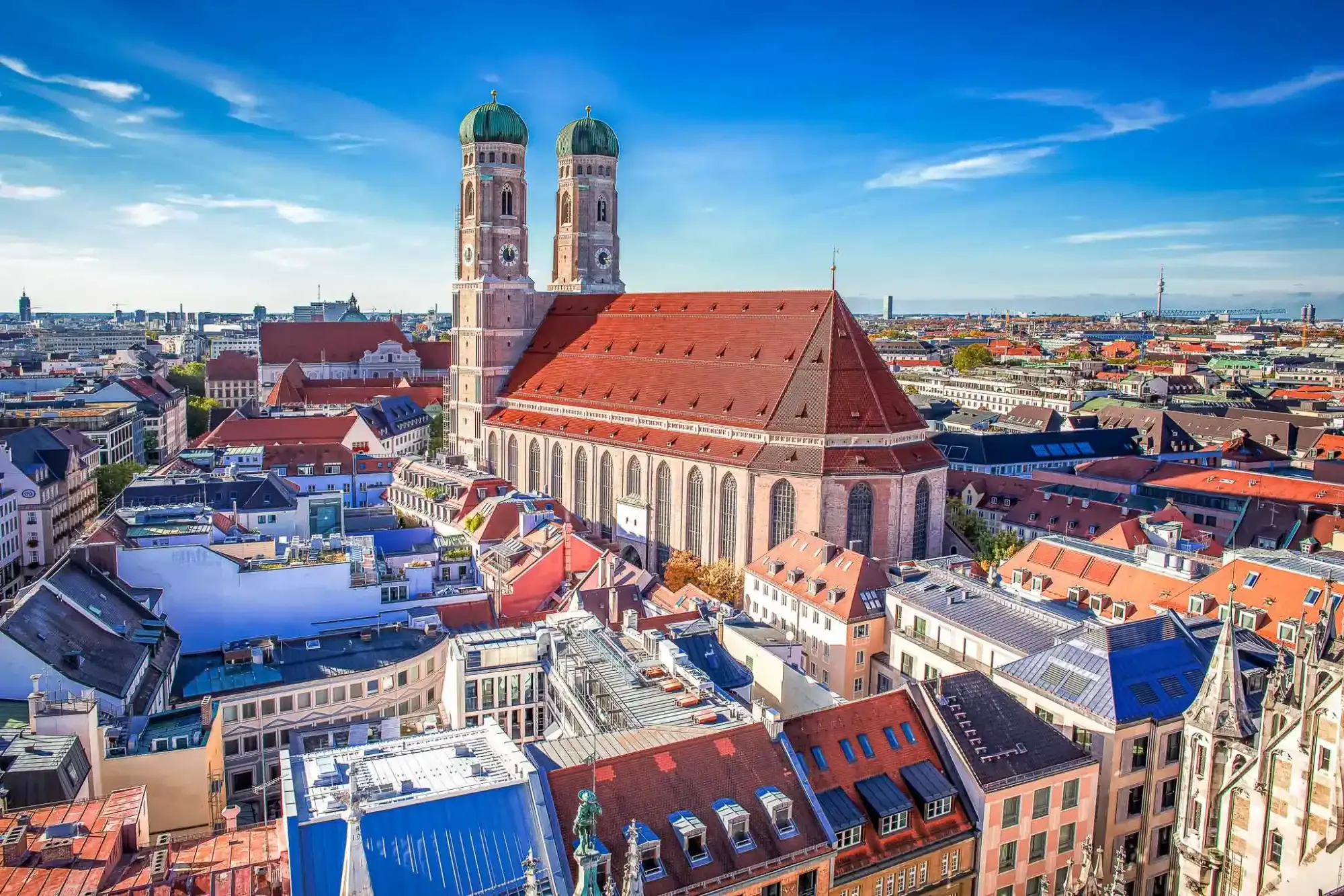 Aerial view of Munich's Frauenkirche (Cathedral of Our Blessed Lady) with its twin green domed towers, surrounded by city roo
