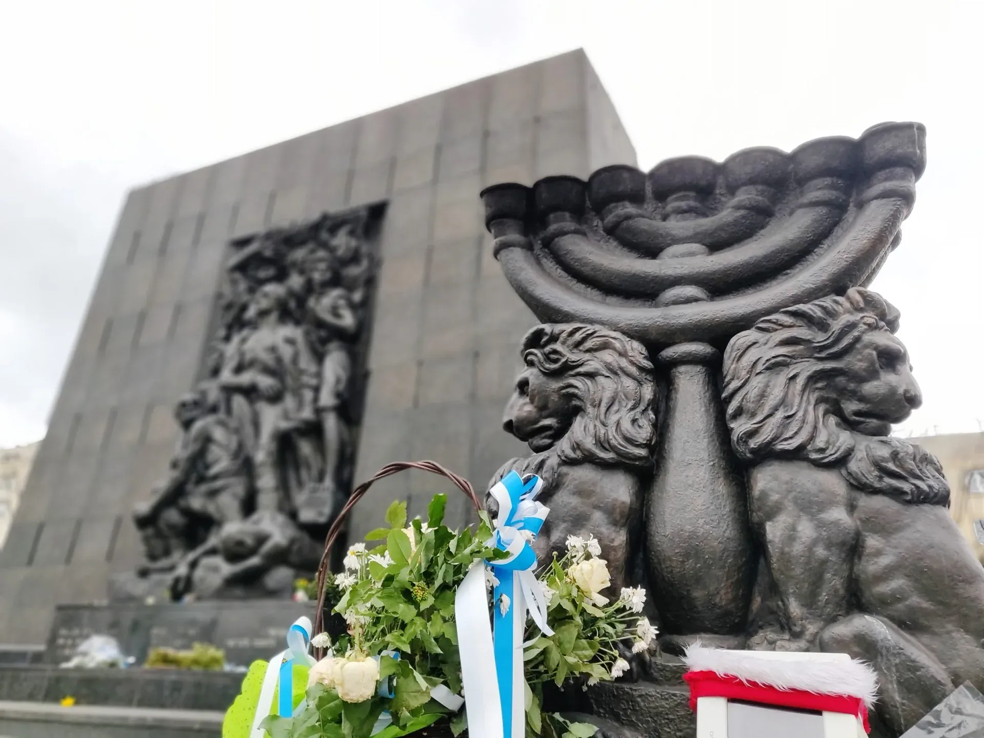Warsaw Ghetto Memorial with menorah and flowers.