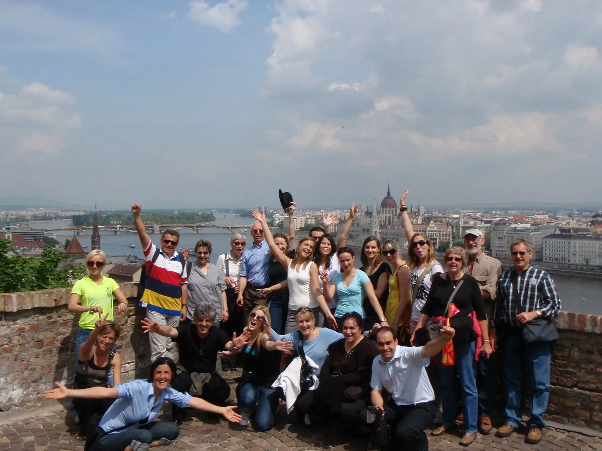 Happy tour group in Budapest, Hungary, with the Parliament Building in the background.