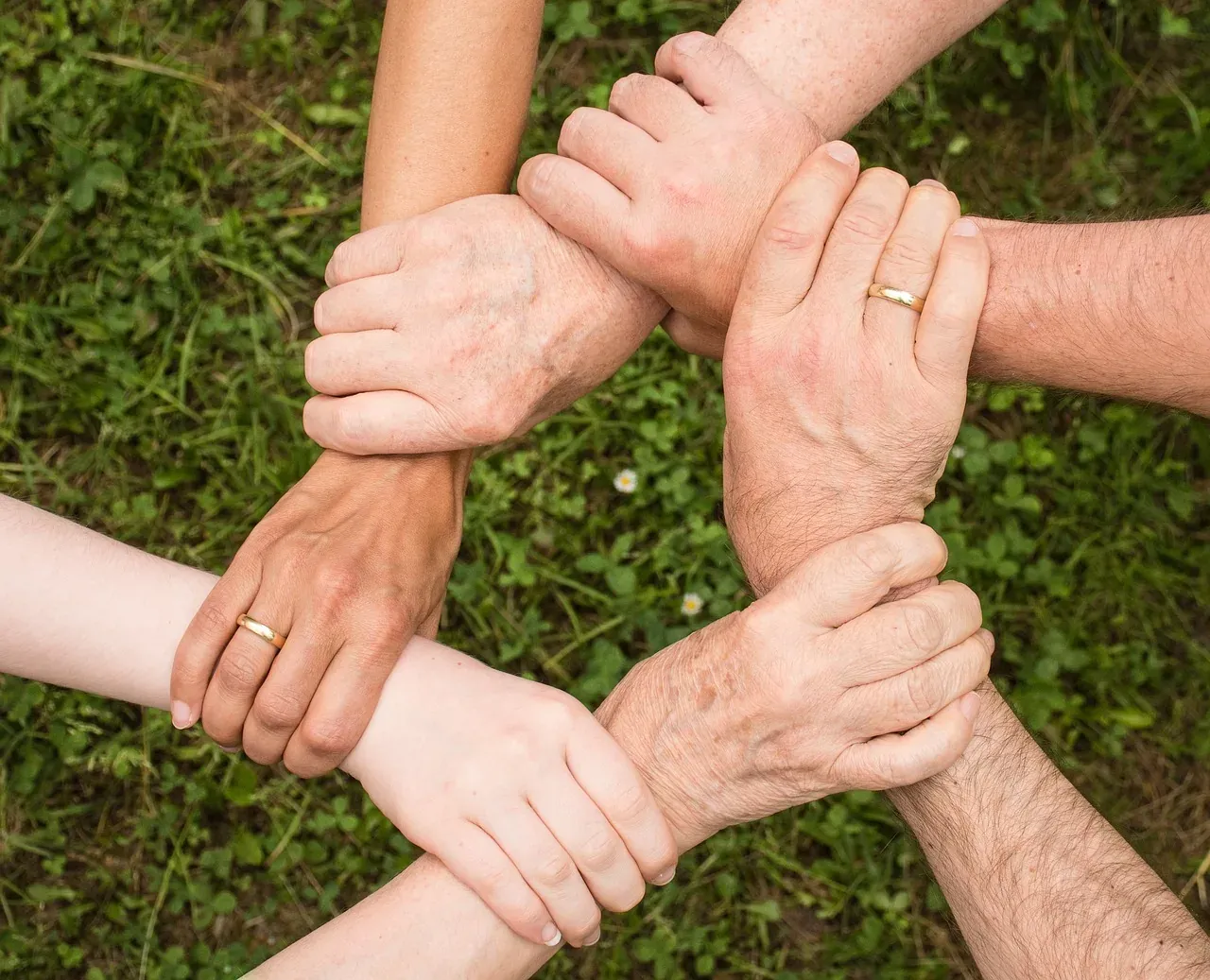 Hands clasped together in a circle, symbolizing unity and teamwork on a group tour in Gdansk.