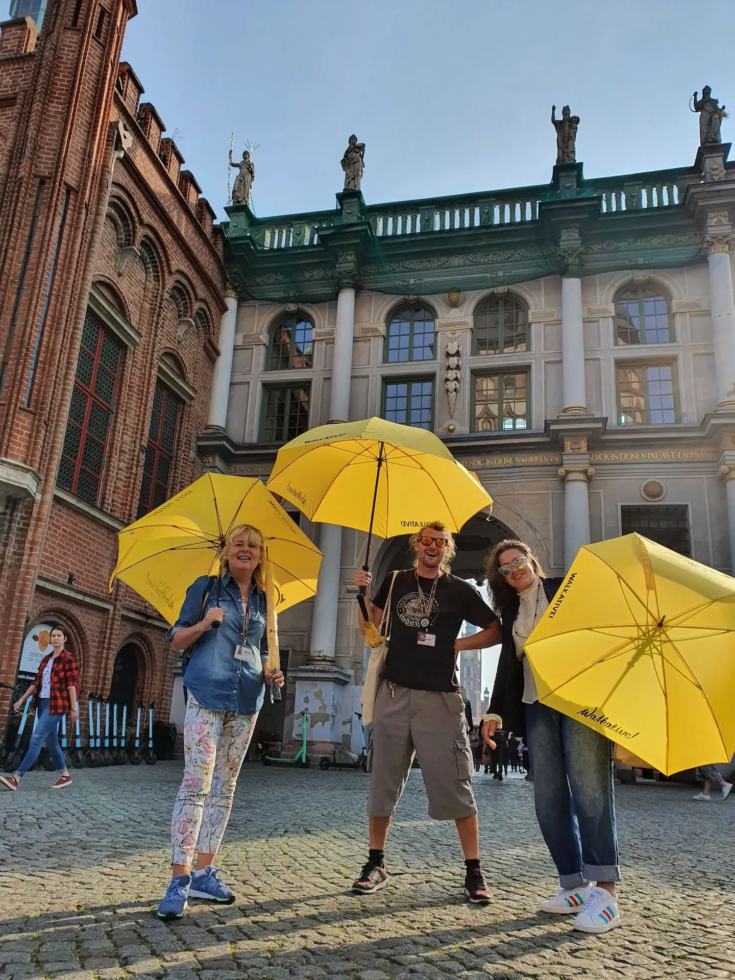 Happy tourists on a guided tour in Gdansk, Poland, standing in front of the Golden Gate.