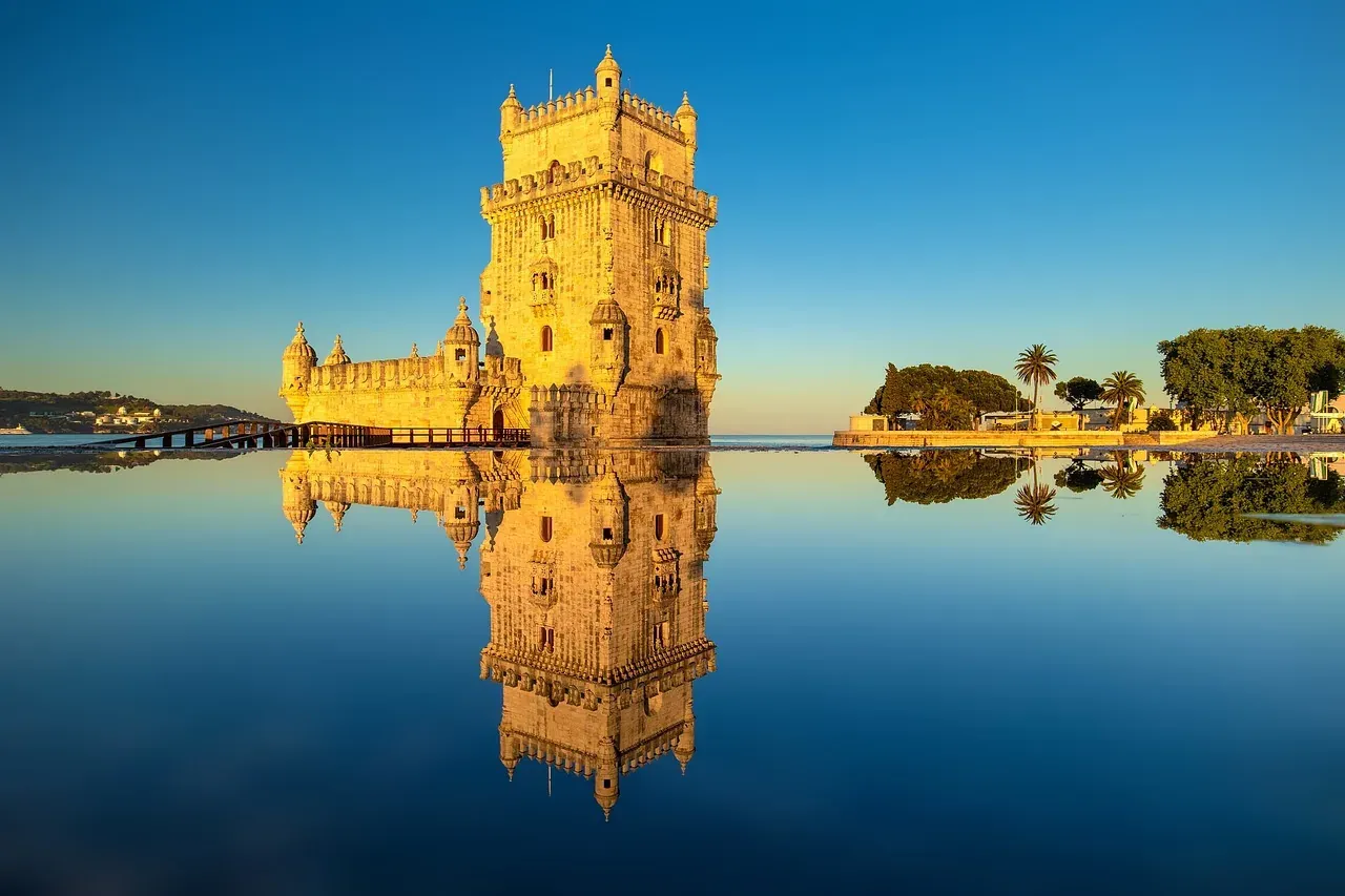 Belém Tower in Lisbon, Portugal, reflected in the water at sunrise.