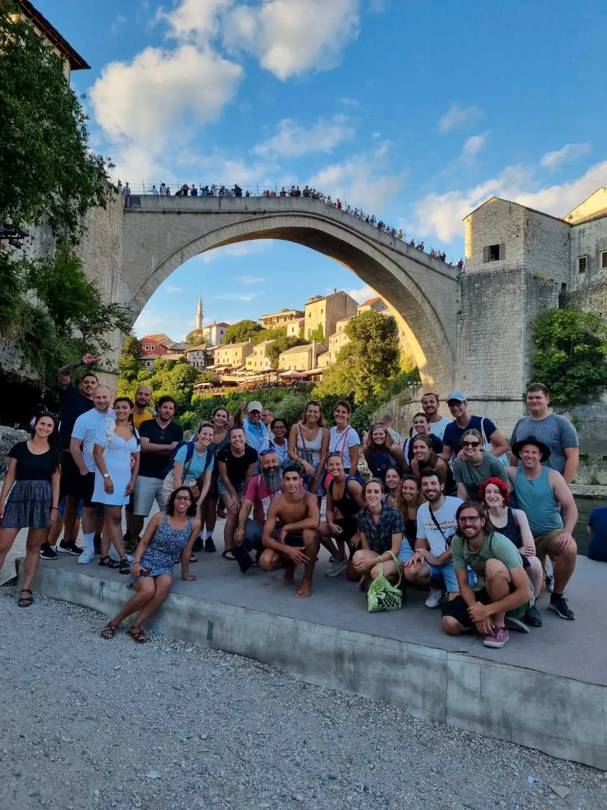 Happy tour group in Mostar, Bosnia and Herzegovina, posing with the Stari Most bridge.