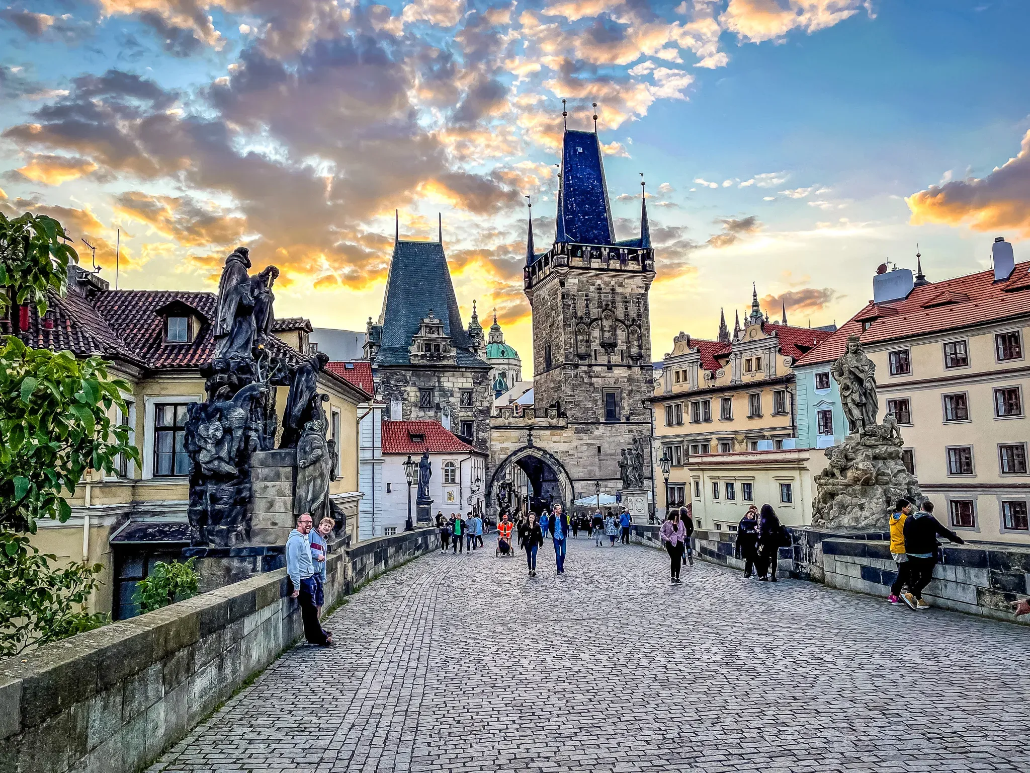 Tourists enjoying a sunset stroll across Prague's Charles Bridge.