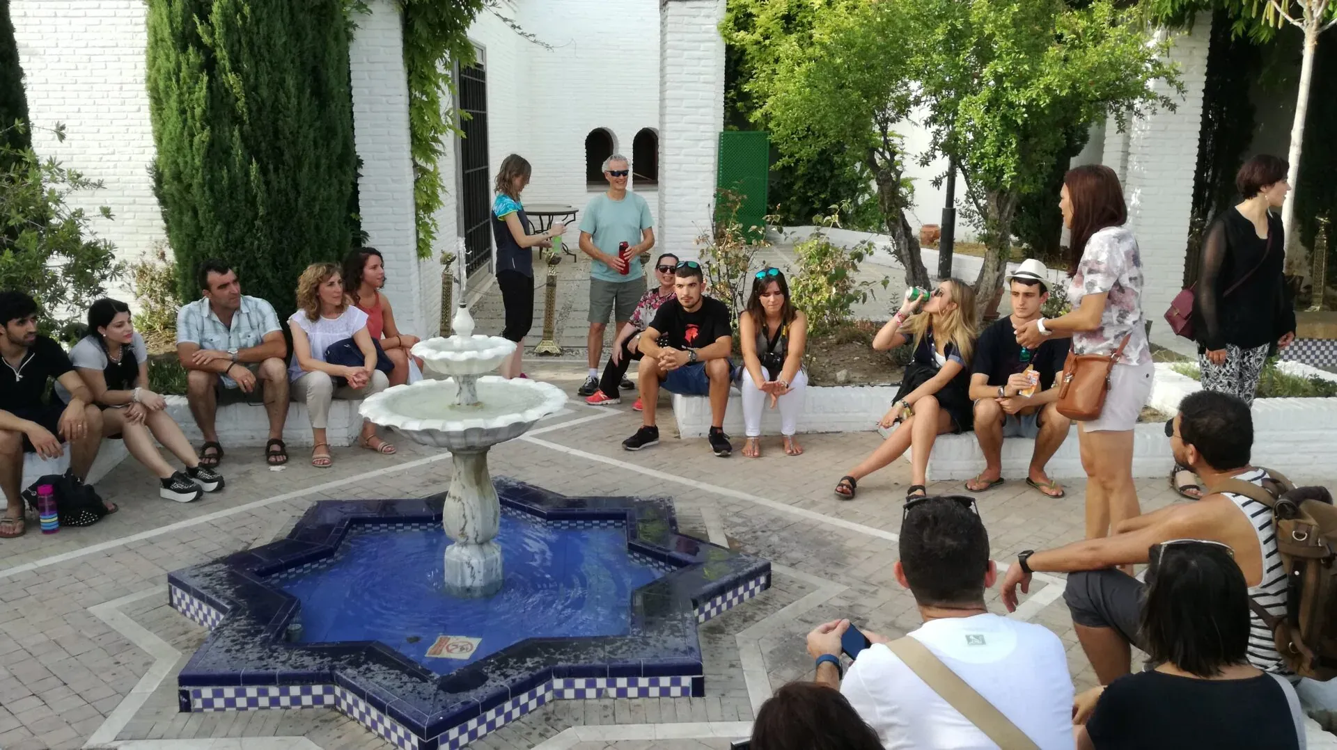 A tour group listens attentively to their guide in a beautiful Seville courtyard.
