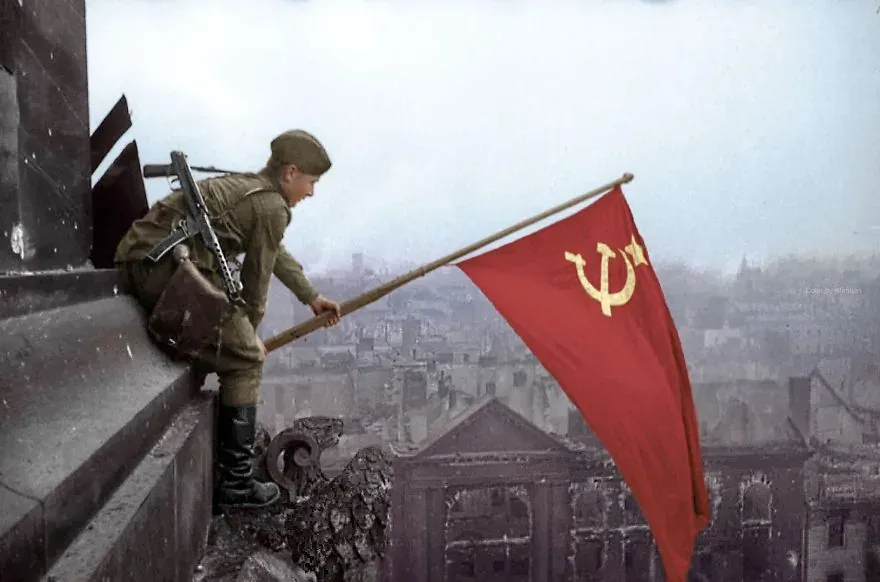 Soviet soldier raising a flag in war-torn Berlin.