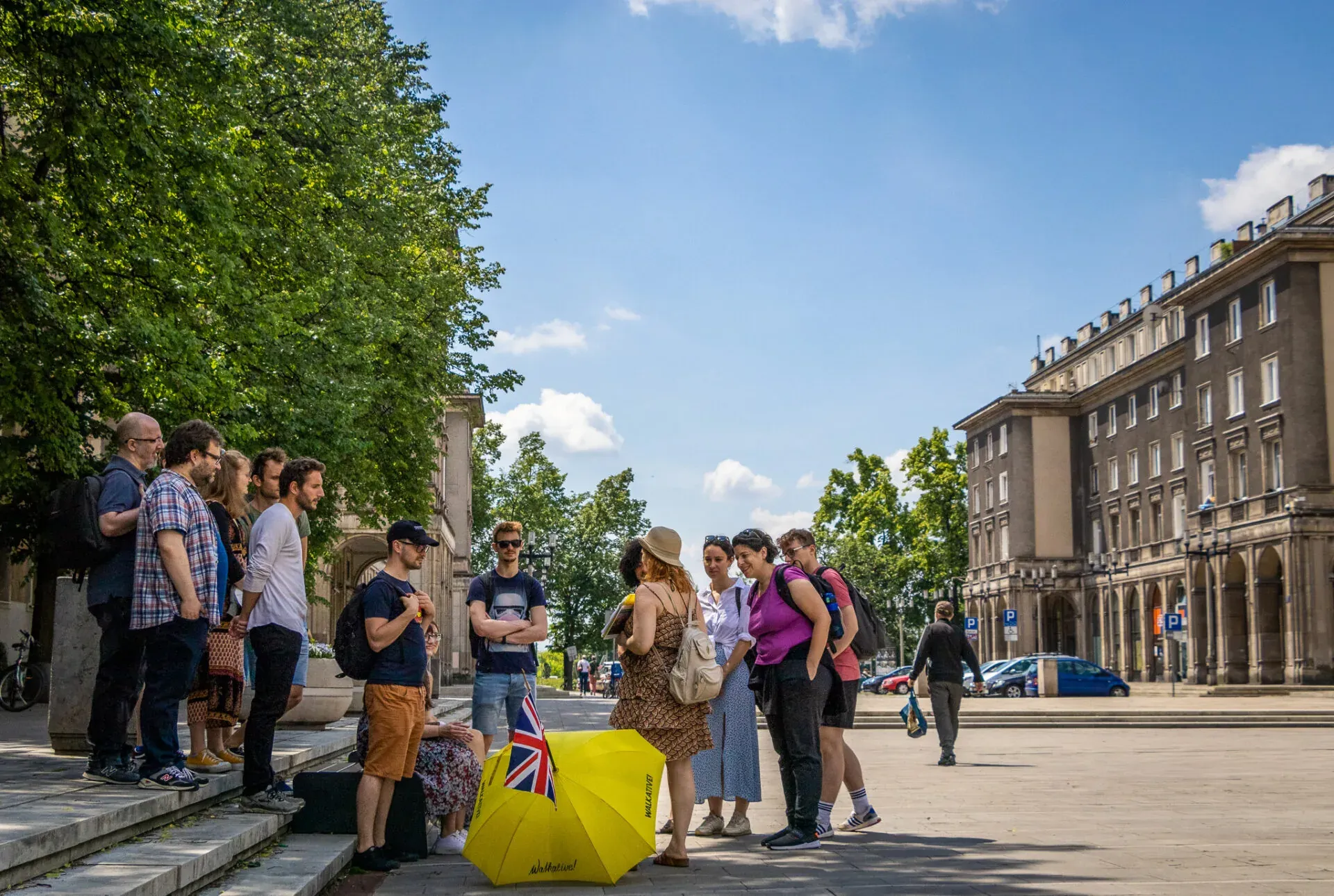A guided tour group explores a sunny city square in Krakow, Poland.