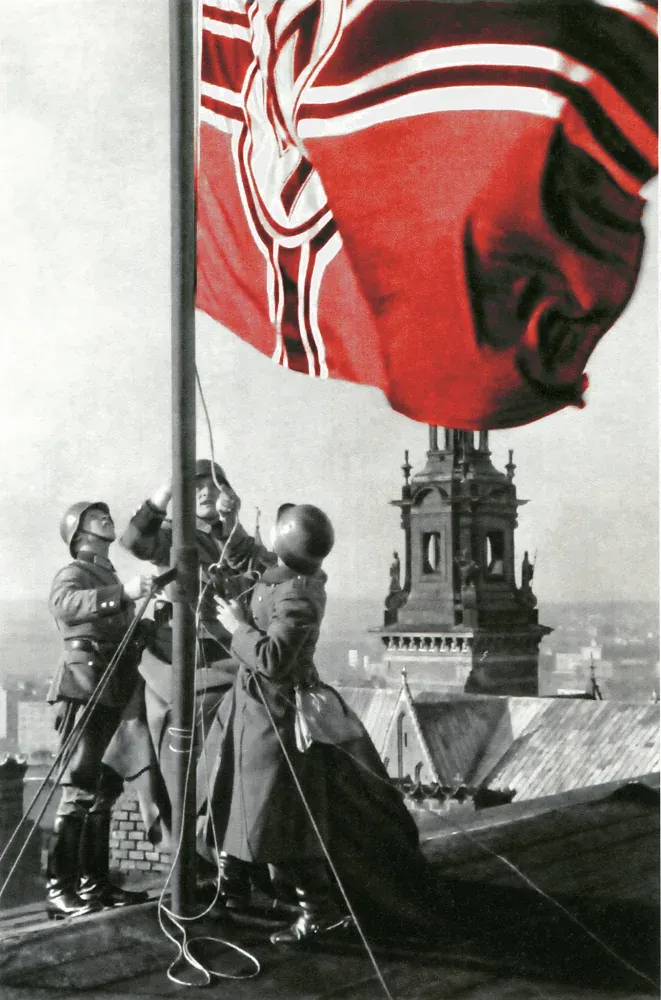 Soldiers raising a flag on a rooftop in Krakow.