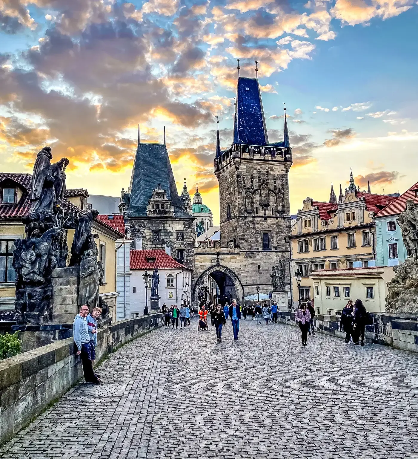 Tourists enjoying a sunset stroll across Prague's Charles Bridge.