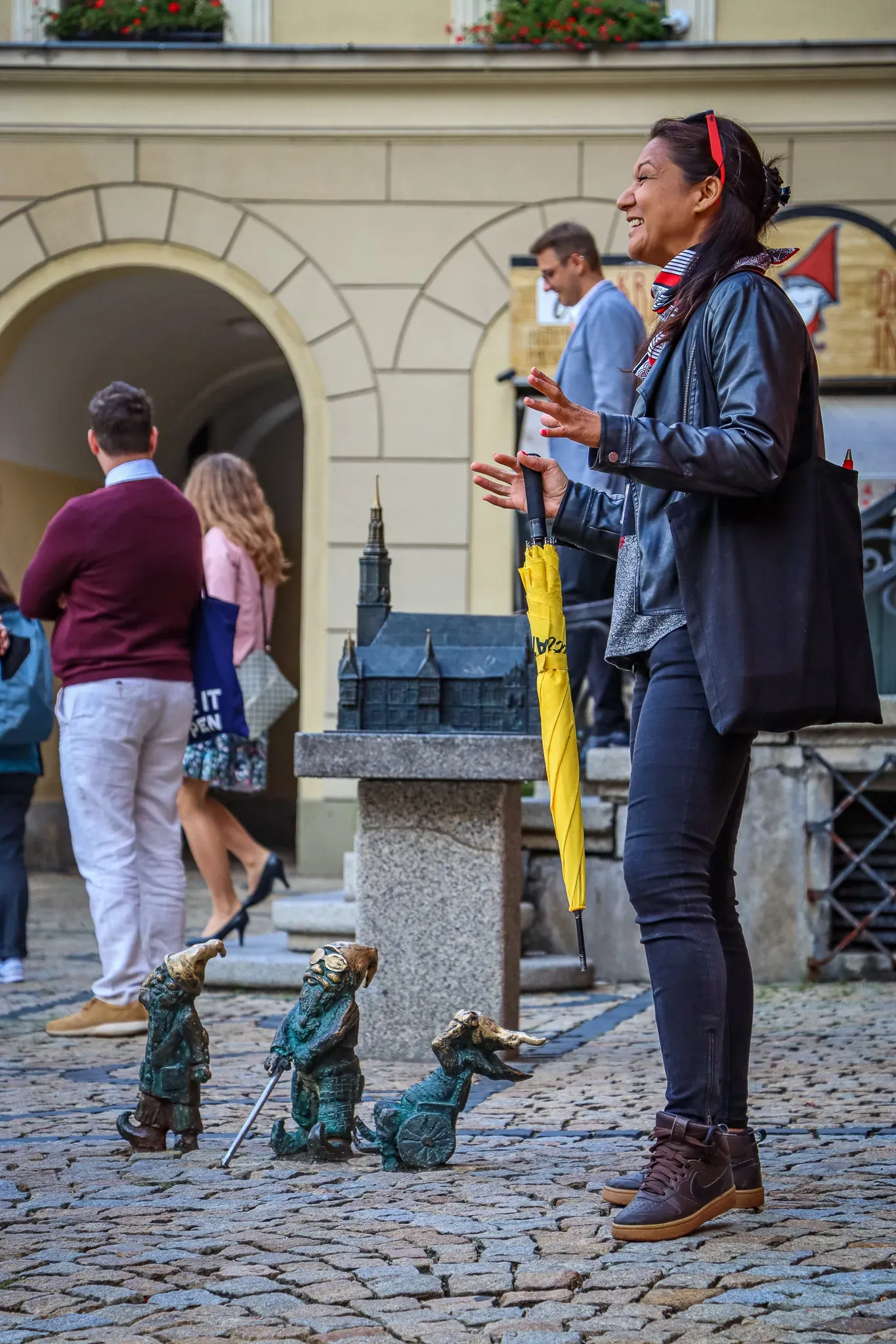 A tour guide in Wroclaw, Poland, points out dwarf statues to a group of tourists.